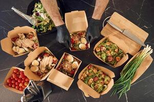 Meat, vegetables,, tomatoes, eggs on the table. Man is packing food into the paper eco boxes. Indoors, restaurant photo