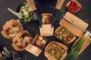 Meat, vegetables, tomatoes,, eggs on the table. Man is packing food into the paper eco boxes. Indoors, restaurant photo