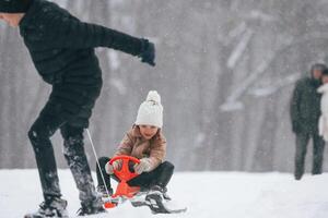 Having fun by riding sled. Happy family is outdoors, enjoying snow time at winter together photo