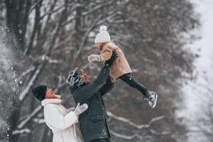 Having fun, holding ,girl on the hands. Mother and father is with daughter have walk outdoors at the winter season photo