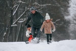 Sled ride.. Mother and father is with daughter have walk outdoors at the winter season photo