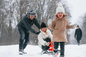 Woman is on sled ride. Happy family is outdoors, enjoying snow time at winter together photo