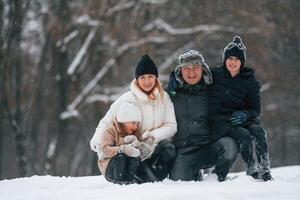 Sitting and looking forward.. Happy family is outdoors, enjoying snow time at winter together photo