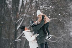 Having, fun,, holding girl on the hands. Mother and father is with daughter have walk outdoors at the winter season photo