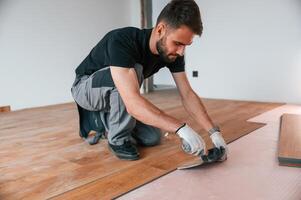 Using the, rubber hammer. Man is installing new laminated wooden floor photo