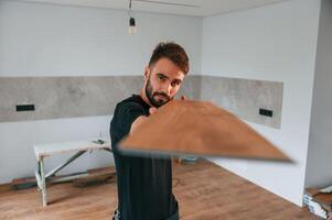 Looking ,at the length of, the plank. Man is installing new laminated wooden floor photo