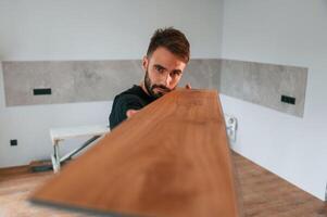 Looking at the length of the plank. Man is installing new laminated wooden floor photo