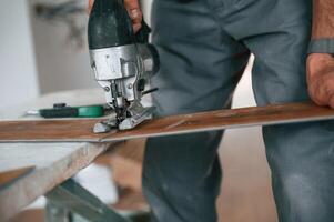 Cutting, the planks. Man is installing new laminated wooden floor photo