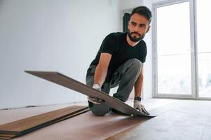 Fitting, the planks.. Man is installing new laminated wooden floor photo