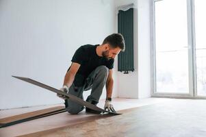 Fitting the planks.. Man is installing new laminated wooden floor photo