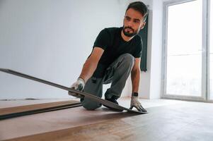 Fitting, the planks. Man is installing new laminated wooden floor photo