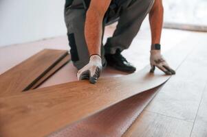 Close up view,. Man ,is installing new laminated wooden floor photo