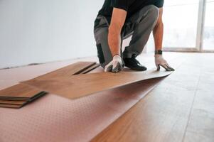 Fitting the planks. Man is installing new laminated wooden floor photo