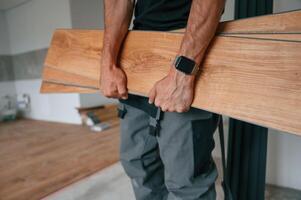 Plank is in ,the hands. Man is installing new laminated wooden floor photo