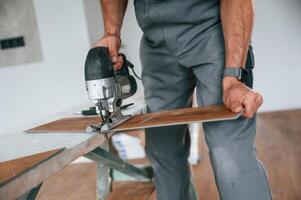 Cutting the, planks. Man ,is installing new laminated wooden floor photo