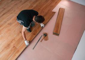 Top view. Man is installing new laminated wooden floor, photo