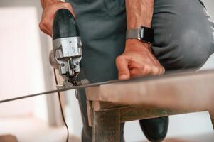 Using ,jigsaw, to cut pieces. Man is installing new laminate wooden floor photo