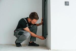 Plumber worker ,installing heating radiator in empty room of a newly built house photo