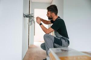 Electrician, is working with wires indoors in the room photo
