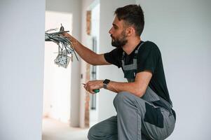Electrician ,is working with wires indoors in the room photo
