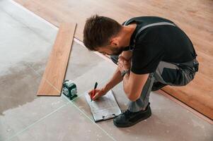 Using the leveler. Man is installing new laminated ,wooden floor photo