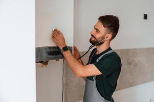 A man, repairs a, boiler. Listens to it using a stethoscope photo