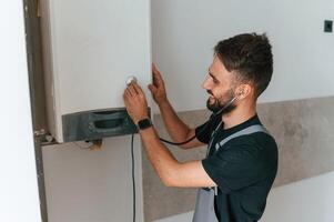 A man repairs a boiler. Listens to it using, a stethoscope photo