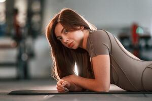 Lying ,down on the yoga mat and resting. Beautiful woman with sport body type is in the gym photo