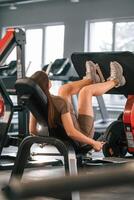 Doing exercises for the legs. Beautiful ,woman with sport body type is in the gym photo