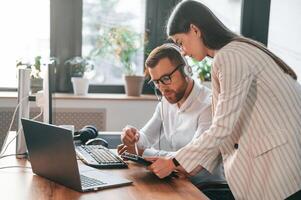 Showing, information on tablet. Two employees are working together in the modern office photo