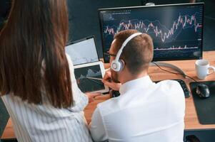 Two, office ,workers are analyzing graphs that on the computer screen photo