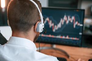 Stock ,exchange graphs on the screen. Man in formal clothes is working in the modern office. Using computer photo