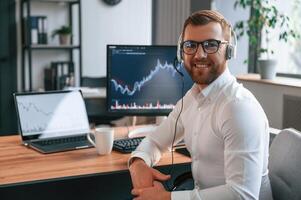 Stock ,exchange graphs, on the screen. Man in formal clothes is working in the modern office. Using computer photo