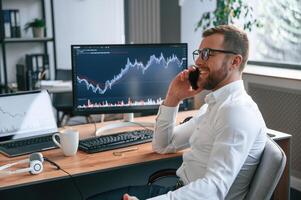 Stock exchange, graphs on the screen. Man in formal clothes is working in the modern office. Using computer photo