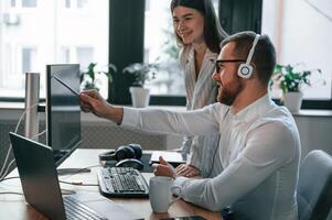 Analyzing information that, is on the screen. Two employees are working together in the modern office photo