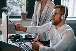 Analyzing, information that is on the screen. Two employees are working together in the modern office photo