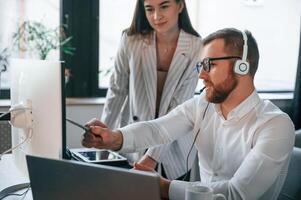 Analyzing, information, that is on the screen. Two employees are working together in the modern office photo