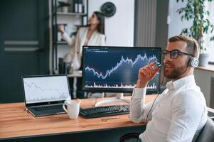 Exchange, graphs on the screen. Two employees are working together in the modern office photo