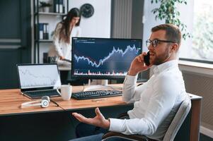 Exchange graphs ,on the screen. Two employees are working together in the modern office photo