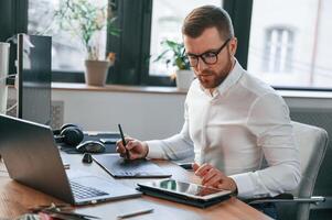 Using, tablet. Man in formal clothes is working in the modern office photo