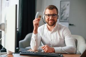 Holding bitcoin in the ,hand. Man in formal clothes is working in the modern office. Using computer photo