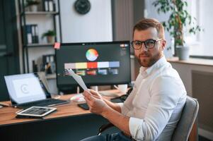 Graphic designer is sitting.. Man, in formal clothes is working in the modern office. Using computer photo