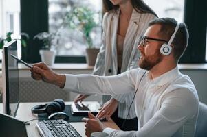 Analyzing information that is on the screen. Two employees are working together in the modern office photo