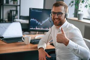 Stock ,exchange graphs,on the screen. Man in formal clothes is working in the modern office. Using computer photo