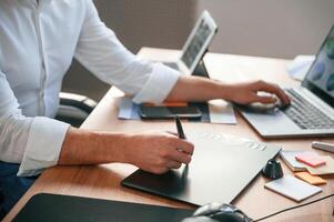 With ,graphic tablet. Close up view of designer's hands. Man in formal clothes is working in the modern office. Using computer photo