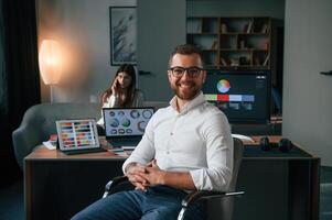 Positive man ,is smiling. Two employees are working together in the modern office photo