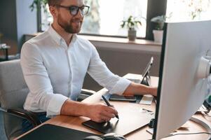 Man in formal clothes is working in the ,modern ,office. Using computer photo
