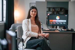 Sitting on the ,chair. Designer's software on the screen. Woman is working in the modern office with computer photo