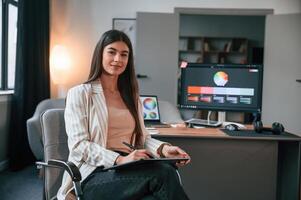 Sitting ,on the chair. Designer's ,software on the screen. Woman is working in the modern office with computer photo