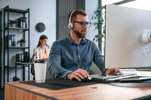 Man is using ,computer. Two employees are working together in the modern office photo